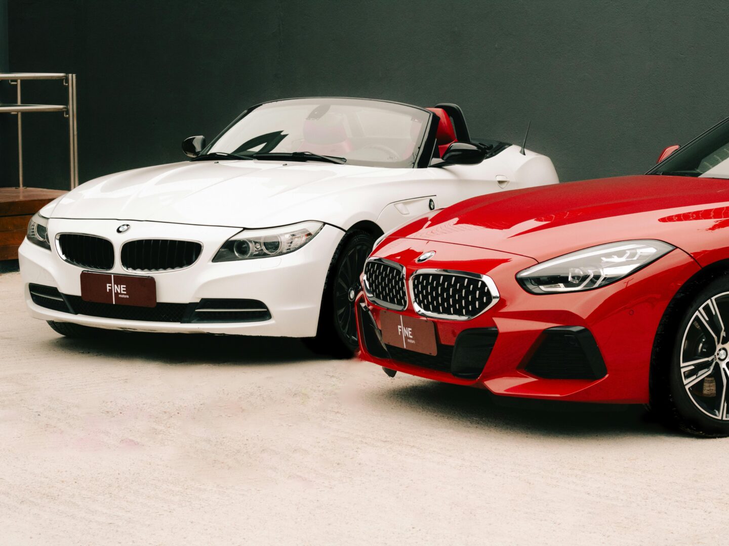 Dynamic shot of luxury red and white convertible cars displayed outdoors for sale.